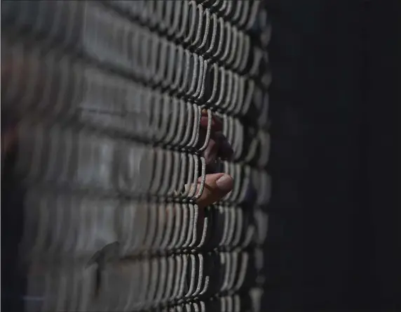  ?? BRYNN ANDERSON — THE ASSOCIATED PRESS ?? A fan holds the fence while watching a spring training baseball practice on Friday, Feb. 17, 2023, in Fort Myers, Fla.