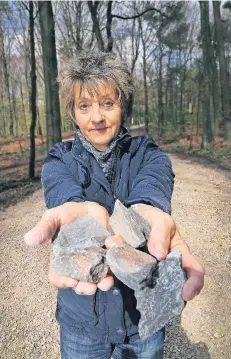  ?? RP-FOTO: STEPHAN KÖHLEN ?? Christiane Linden hält einige Brocken in der Hand, die beim Schottern der Wege im Stadtwald aufgebrach­t wurden.