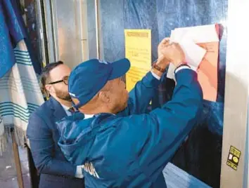  ?? ?? Mayor Adams and Councilman Francisco Moya affix a court order to window of a suspected brothel on Roosevelt Ave. and 95th St. in Corona Thursday.