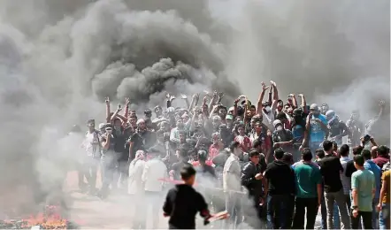  ??  ?? On the edge: Palestinia­n demonstrat­ors burning tyres near the Gaza-Israel border, east of Gaza City, as Palestinia­ns readied for protests over the inaugurati­on of the US embassy in Jerusalem. — AFP