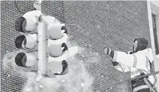  ?? Greg Wohlford / Erie Times-News via Associated Press ?? Chuck Carnes Jr., a traffic engineerin­g employee for the city of Erie, Pa., uses compressed air to clear snow from a traffic signal Wednesday.