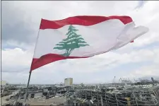  ?? HASSAN AMMAR — THE ASSOCIATED PRESS ?? A Lebanese flag set by citizens flies in front the site of Tuesday’s explosion that hit the seaport of Beirut, Lebanon, Sunday, Aug. 9, 2020. Lebanon’s informatio­n minister resigned on Sunday as the country grapples with the aftermath of the devastatin­g blast that ripped through the capital and raised public anger to new levels.