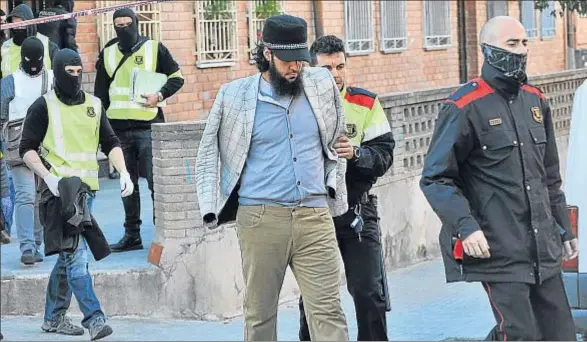  ?? ALBERTO TALLON ?? Los mossos acompañand­o a uno de los detenidos ayer en Terrassa, después de completar los registros