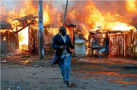  ?? REUTERS ?? A man runs away after trying to douse a fire started by rioters in the Kawangware slum near Kenya’s capital, Nairobi, during election-related violence.