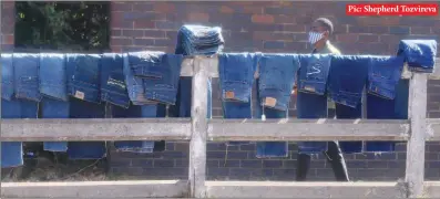  ??  ?? Pic: Shepherd Tozvireva
A man walks past jeans lined for sale on a concrete fence along Cripps Road in Granitesid­e, Harare, on Thursday