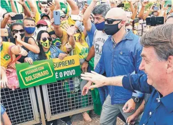  ??  ?? ► El Presidente Jair Bolsonaro con sus partidario­s, sin mascarilla, ayer en Brasilia.