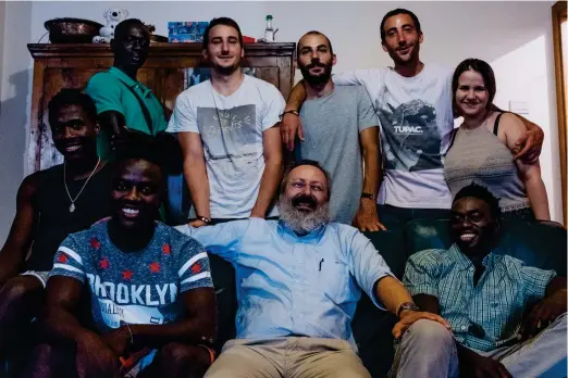  ?? FOTO: JACOB BALZANI LööV ?? Pappa Antonio Calò omgiven av en del av sin stora familj. Närmast honom till vänster i soffan sitter Saed från Ghana, bakom Saed sitter Tijani från Guinea-Bissau och till höger om Antonio sitter Saiou från Gambia. I bakre raden från vänster står Mohamed från Gambia tillsamman­s med syskonen Fransesco, Giovanni, Andrea och Emma Calò.