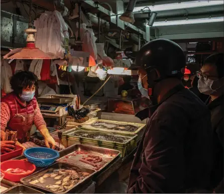  ??  ?? Residents wearing face masks purchase seafood at a wet market in Macau, China. However China, where Covid originated, now appears to have virtually eliminated the disease