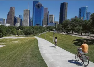  ?? Michael Ciaglo / Houston Chronicle ?? Cyclists pedal through Buffalo Bayou Park next to Allen Parkway on Monday. A new partnershi­p between city and county officials seeks to improve bike and pedestrian access to downtown.