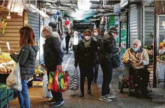  ?? Cecilia Fabiano / Associated Press ?? People wear masks while shopping at an open-air market Thursday in Rome. Authoritie­s in regions including Italy's three largest cities have imposed curfews in a bid to slow the spread.