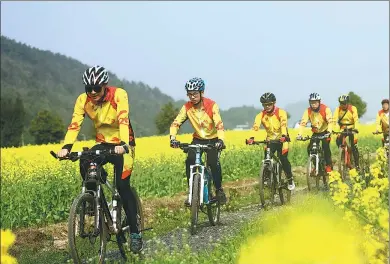  ?? LIU XINRONG / XINHUA ?? Cyclists ride through blossoming rapeseed flower fields in Hengyang, Hunan province, on Saturday. Many visitors have come to enjoy the natural beauty as well as the recent unseasonab­ly warm weather in the region.