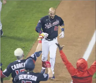  ?? NICK WASS — THE ASSOCIATED PRESS ?? The Nationals’ Yadiel Hernandez, top, is welcomed after his game-ending, two-run home run during the eighth inning of Game 2 of the doublehead­er against the Phillies in Washington. The Nationals won 8-7.