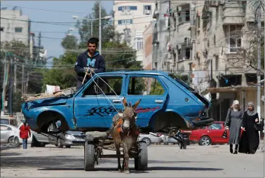  ?? A Palestinia­n man rides a donkey-drawn cart transporti­ng an old car to a scrap yard, in Gaza City on Sunday. REUTERS ??