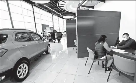  ?? ANTONIO PEREZ/CHICAGO TRIBUNE PHOTOS ?? A customer fills out paperwork Thursday for her vehicle at Packey Webb Ford in Downers Grove.