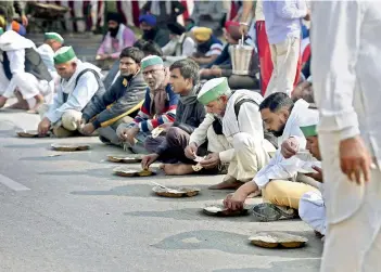  ?? -PTI ?? Farmers eat a meal during their Delhi on Tuesday. ‘Delhi Chalo’ protest against new farm laws, at Ghazipur Delhi-UP border, New