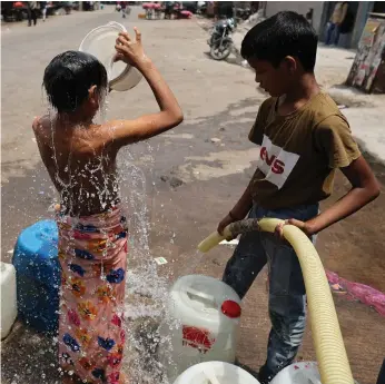  ?? Reuters ?? Boys cool down with water from a municipal tanker in New Delhi yesterday