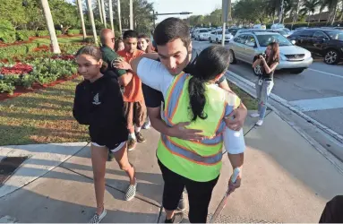  ?? OLIVIA VANNI/NAPLES DAILY NEWS ?? A crossing guard hugs a student near Marjory Stoneman Douglas High School on Wednesday.