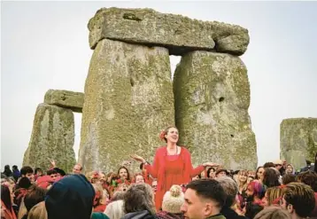  ?? FINNBARR WEBSTER/GETTY ?? Summer solstice: A woman breaks out in song Tuesday at Stonehenge in Wiltshire, England. Thousands of revelers greeted the solstice, the longest day of the year in the Northern Hemisphere. It was the first time revelers were permitted to gather for the solstice since 2019 because of the pandemic. Stonehenge was built 3,500 to 5,000 years ago.