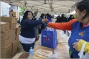  ?? JOSHUA BESSEX — THE ASSOCIATED PRESS ?? Yvonne King, left, hands out bags of bread to community members Tuesday near the Tops Friendly Market in Buffalo, N.Y. While Tops is temporaril­y closed during the shooting investigat­ion, the community is working to make sure residents don't go without.