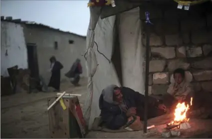  ?? KHALIL HAMRA, THE ASSOCIATED PRESS ?? A Palestinia­n man and his son warm themselves by a fire on the outskirts of the Khan Younis refugee camp, southern Gaza Strip.