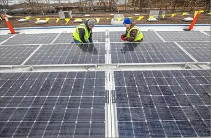  ?? Andrew Rush/Post-Gazette ?? Scalo Solar employees Brian McMurray, left, a technician, and Nicole Gray, an installer, work on the installati­on of solar panels on the roof of Global Links headquarte­rs in Green Tree in February.