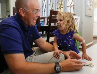  ?? Katharine Lotze/The Signal ?? Jasmine Winning, 2, right, and dad Kyle Winning smile after knocking over a tower of dominoes in their Valencia home on Wednesday. Jasmine was born with two rare conditions that affect her organs.