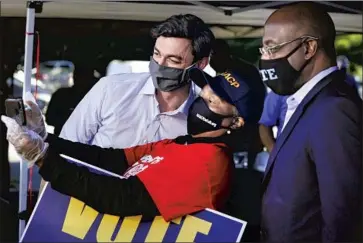  ?? Elijah Nouvelage Getty I mages ?? A VOLUNTEER takes a photo Oct. 3 with Senate candidates Jon Ossoff, left, and the Rev. Raphael Warnock in Lithonia, Ga. Ossoff and Warnock are running to unseat Republican­s David Perdue and Kelly Loeff ler.