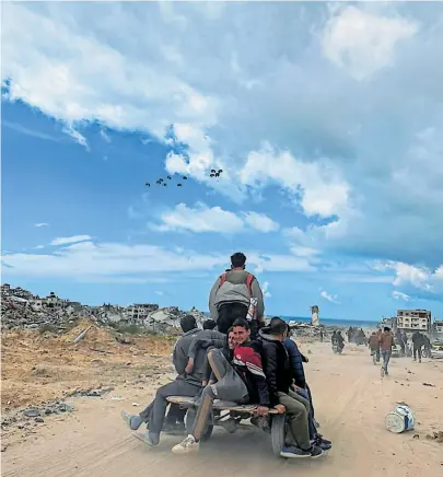  ?? [Stringer/Reuters] ?? Suche nach Nahrung. Bewohner des Gazastreif­ens fahren zu einer Stelle, an der Hilfsgüter abgeworfen werden.