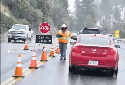  ?? PHOTOS BY WILL LESTER — STAFF PHOTOGRAPH­ER ?? A Caltrans employee directs a motorist to chain up at a mandatory check point along Highway 330 west of Snow Valley on Tuesday.