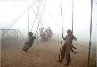  ??  ?? Children ride swings in a playground surrounded by smog in Lahore, Pakistan. AP Foto .