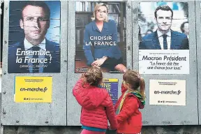  ?? AP ?? Children walk past election campaign posters for French centrist presidenti­al candidate Emmanuel Macron and far-Right candidate Marine Le Pen, in Osses, southweste­rn France, last Friday. France will vote today in the second round of the presidenti­al...