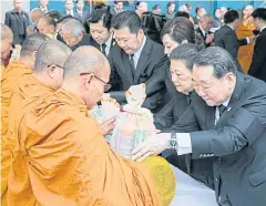  ??  ?? Charoen Pokphand (CP) Group boss Dhanin Chearavano­nt leads his staff in presenting alms to monks to make merit for the late monarch.