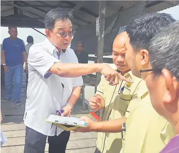  ??  ?? Abdul Karim (left) seen at the Kampung Beliong jetty yesterday with local officials and villagers.