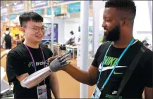  ?? FENG YONGBIN / CHINA DAILY ?? A staff member of an enterprise demonstrat­es the use of an intelligen­t bionic hand to a visitor on Monday at the Canton Fair in Guangzhou, Guangdong province.