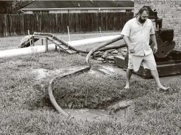  ?? Elizabeth Conley / Staff photograph­er ?? Walt Stelly demonstrat­es the pump and dam system he created to protect his Winnie home onwednesda­y. Ahead of Laura, he encircled his twice-flooded home with an irrigation tube and pumped it full of water to act like a dam. He filled it back up ahead of Beta, too, and hooked up two pumps to bail out any water inside the barrier.