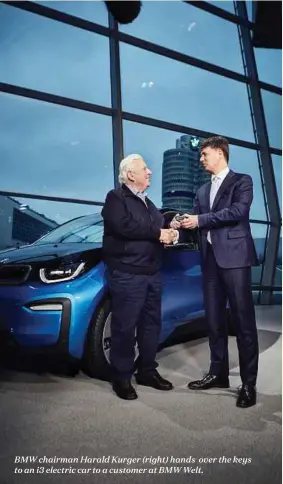  ??  ?? BMW chairman Harald Kurger (right) hands over the keys to an i3 electric car to a customer at BMW Welt.