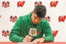  ?? OMAHA (NEB.) WORLD-HERALD LEADER PHOTO BY CHRIS MACHIAN VIA AP ?? Omaha Westside linebacker Teddy Rezac signs a letter of intent to play for Notre Dame on Dec. 20. Major college football’s early signing period, which was instituted in 2017, is moving from late December to the week before conference championsh­ip games starting this fall.