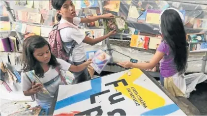  ?? AFP ?? Festival de lectura.
Tres chicas eligen libros de una enorme estantería en la favela Babilonia, de Río.