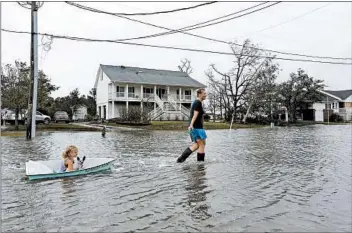  ?? TOM COPELAND/AP ?? Jessie Lawrence pulls her daughter, Kinsley Spaid, as floodwater­s creep up Saturday in Davis, N.C.