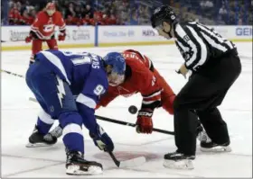  ?? CHRIS O’MEARA — THE ASSOCIATED PRESS ?? Linesman Libor Suchanek (60) drops the puck for Tampa Bay Lightning center Steven Stamkos (91) and Carolina Hurricanes left wing Jordan Martinook (48) during the first period of an NHL preseason hockey game Tuesday in Tampa, Fla.