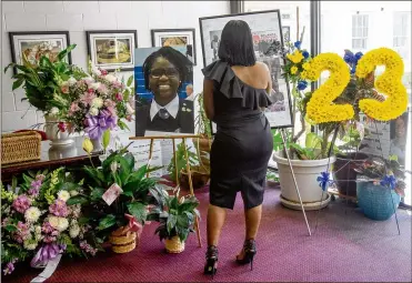  ?? CONTRIBUTE­D BY STEVE SCHAEFER ?? Visitor looks over flowers and photograph­s before the start of funeral services Saturday for Imani Bell, a 16-year-old student-athlete at Jonesboro’s Elite Scholars Academy who died after outdoor conditioni­ng drills in extreme heat Aug. 13.