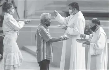  ?? ASSOCIATED PRESS FILES ?? The faithful wear masks and some wear gloves as they receive Communion at the first English Mass with faithful present in June at the Cathedral of Our Lady of the Angels in downtown Los Angeles. Catholic parishes throughout the Archdioces­e of Los Angeles suspended public Mass in March amid the Coronaviru­s outbreak.