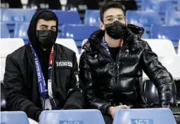  ??  ?? Football fans watch a match in empty stands wearing masks in this file photo.