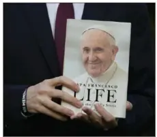  ?? Gregorio Borgia/Associated Press ?? Italian journalist and writer Fabio Marchese Ragona holds a copy of “Life: My Story Through History” on Thursday prior to the start of an interview. Pope Francis says he has no plans to resign and isn’t suffering from any health problems that would require doing so.