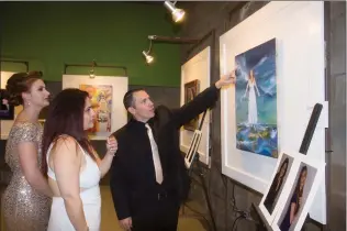  ?? Perry Smith/The
Signal ?? From left, Empowering HeArts honoree Kiya Ramsey, past honoree Martha Aguilera, and Kiya’s husband, Tom Ramsey, look at the art work created for the event Saturday at the Empowering HeArts gala inside the Savia Community Center. The event raises money...