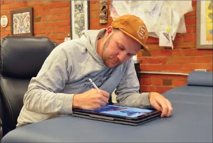  ?? NEWS PHOTO MO CRANKER ?? Lucky Squid tattoo artist Olie Larsen draws up some flash artwork Thursday at the studio. The shop is hosting a fundraisin­g event all day Saturday in conjunctio­n with the Medicine Hat Skateboard Associatio­n to raise money to help fight human traffickin­g.