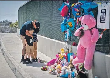  ?? Photograph­s by Allen J. Schaben Los Angeles Times ?? GEORGE AGUILAR prays with his sons, Jackson and Jacob, next to a memorial on the Walnut Avenue overpass of the 55 Freeway, where a 6-year-old boy was fatally shot in an apparent road rage incident Friday.