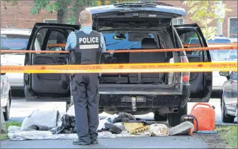  ?? CP PHOTO ?? A police officer looks towards a black SUV that has had its contents removed at a crime scene outside the Metropolis in Montreal on September 5, 2012.