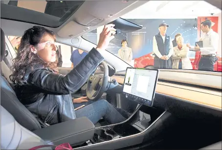  ?? STAFF FILE PHOTO ?? Annelies Lindemans, 47, of San Jose, a Tesla Model 3 reservatio­n holder, adjusts the mirror on a display model of the car at the electric sedan’s first appearance in a Tesla showroom in January.