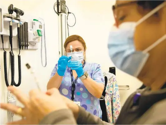  ?? STACEY WESCOTT CHICAGO TRIBUNE ?? Nurses Noemy Godina (left) and Lydia Weber fill syringes with COVID-19 vaccines at Cook County Health North Riverside Health Center in Illinois.